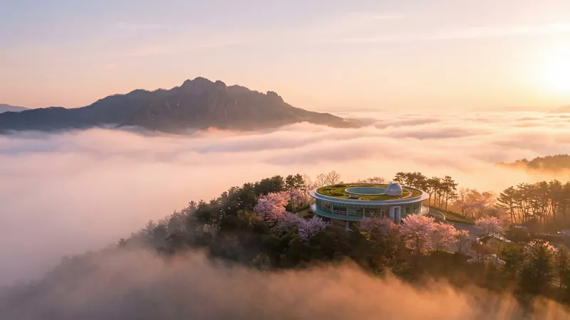 Round building on a hill above a sea of fog