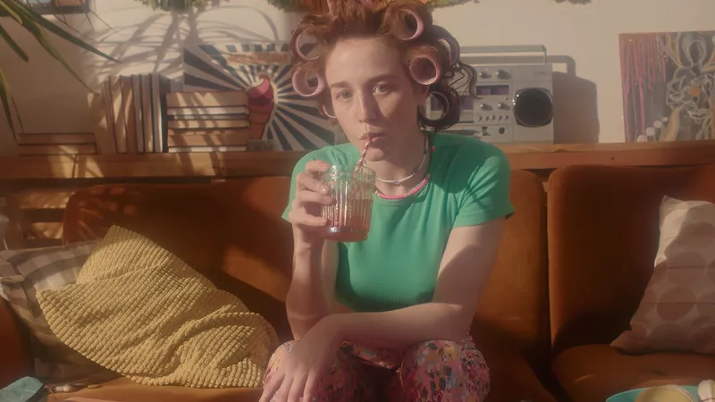 Woman in hair curlers sipping a drink on a retro sofa